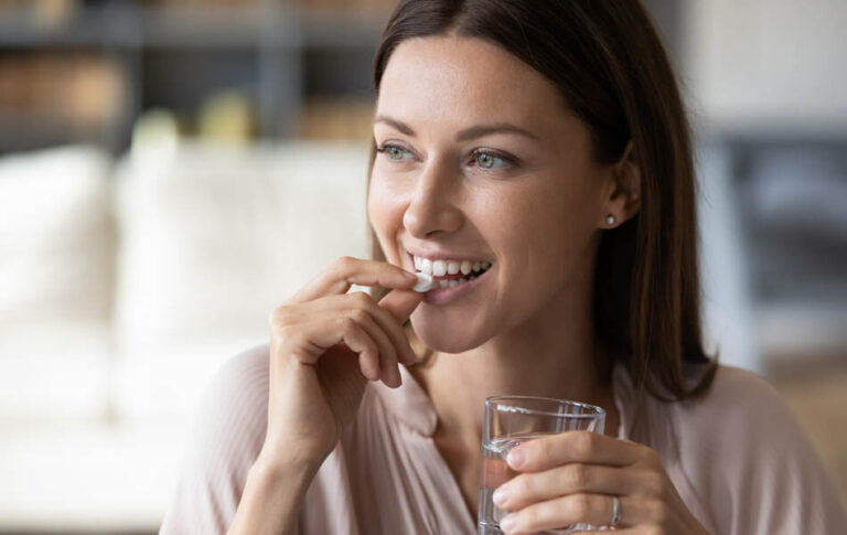 Close,Up,Smiling,Woman,Taking,White,Round,Pill,,Holding,Water